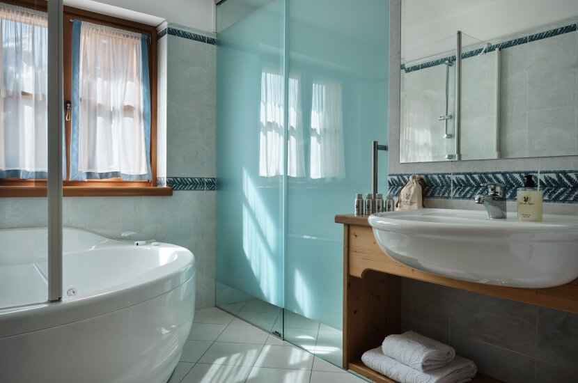 A clean bathroom featuring a white oval bathtub, sink with towels, shower behind glass, and blue chevron tiles.