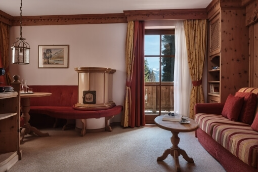 Cozy room with red and gold decor, featuring a red couch, artwork, and a large window with matching curtains.