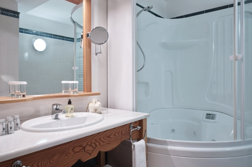 Ein ruhiger Badezimmerbereich mit einer weißen Badewanne, Waschbecken, Spiegeln und verschiedenen Toilettenartikeln.