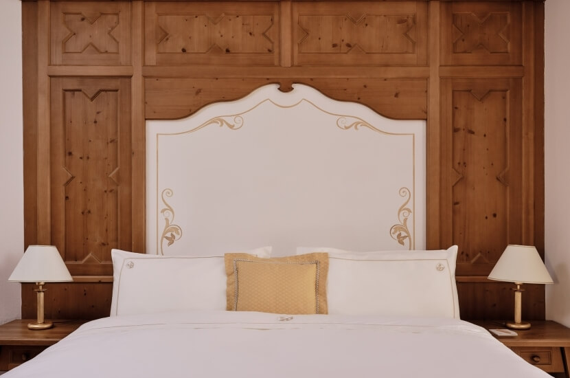 Serene bedroom with a large bed, white headboard, yellow pillow, wooden nightstands, and soft lighting for a cozy atmosphere.