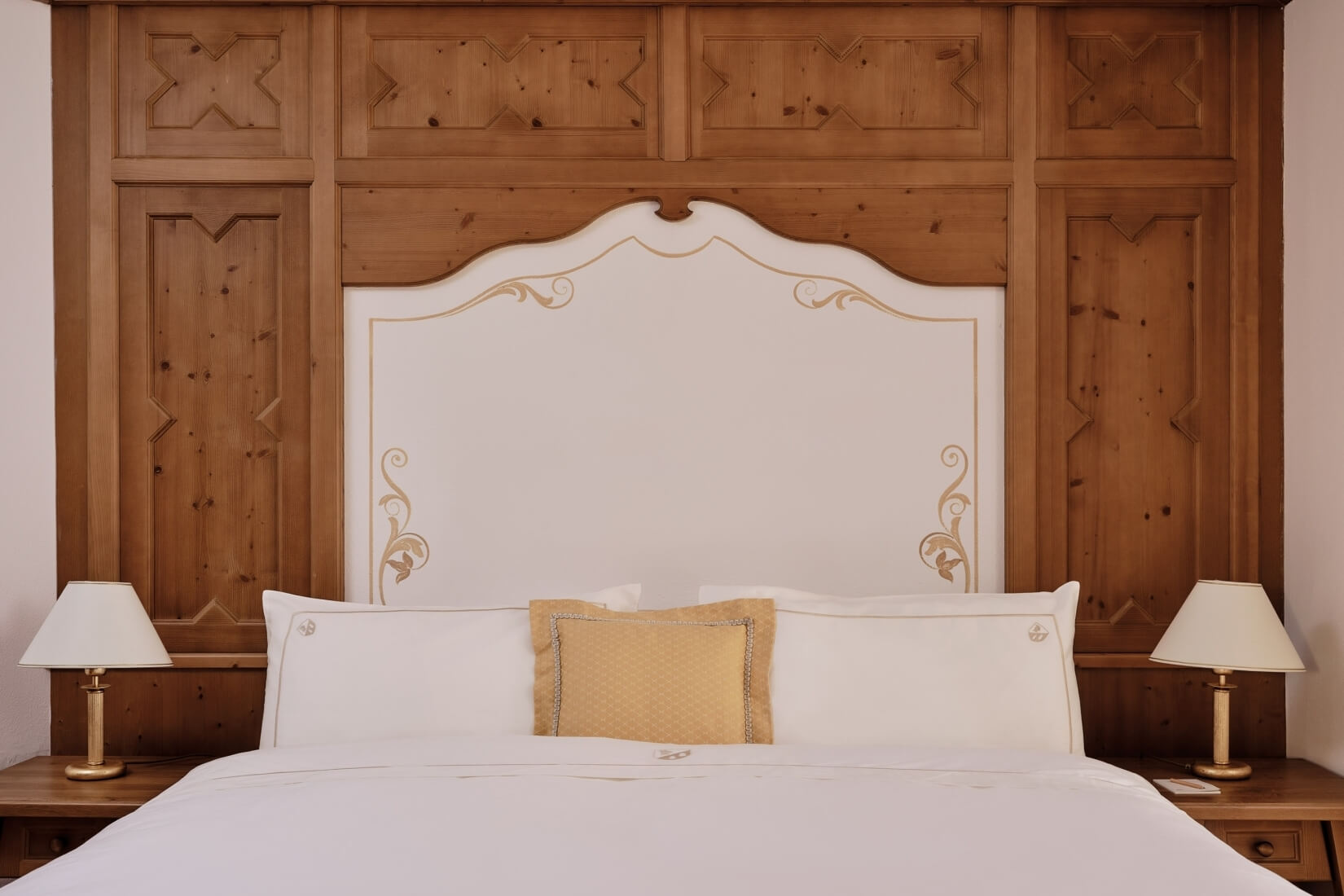 Spokojna sypialnia z dużym łóżkiem, białą pościelą, żółtą poduszką i eleganckimi lampami na nocnych