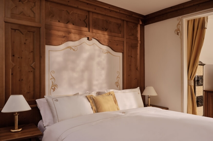 Serene bedroom with a large bed, elegant furnishings, warm lighting, and a cozy atmosphere, featuring a doorway to another room.