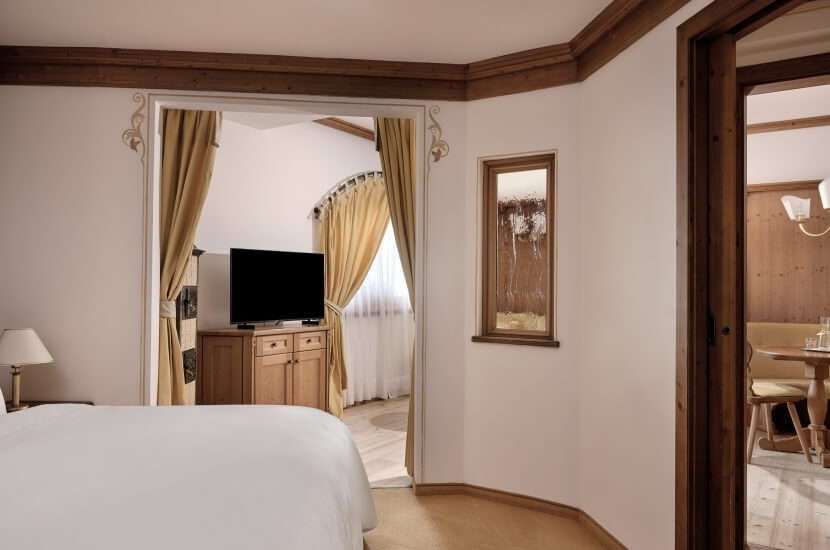Serene room with a bed, television, dining area, warm tones, and elegant decor, creating a cozy and inviting atmosphere.