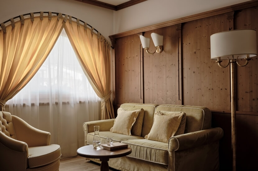 Cozy living room with a tan couch, wooden accents, a coffee table, and elegant decor, exuding warmth and comfort.