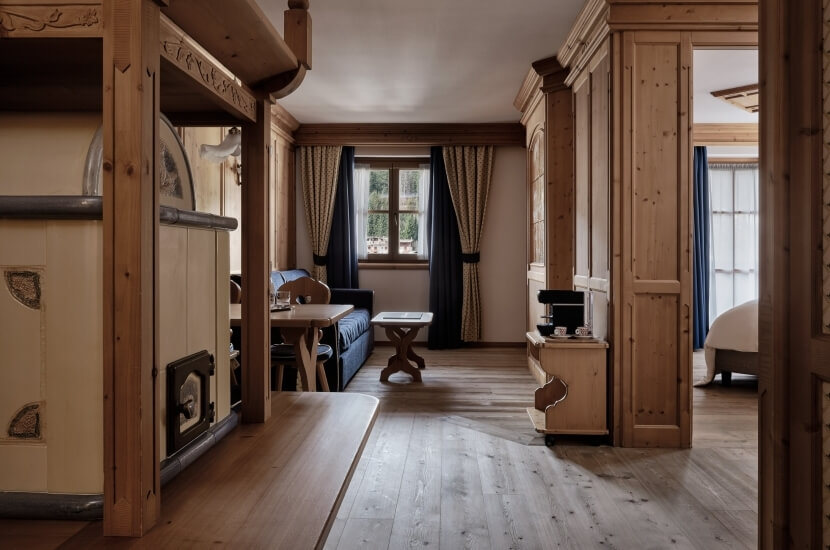 Camera rustica e accogliente con area salotto, letto, finestre luminose e mobili in legno chiaro. Atmosfera calda e invitante.