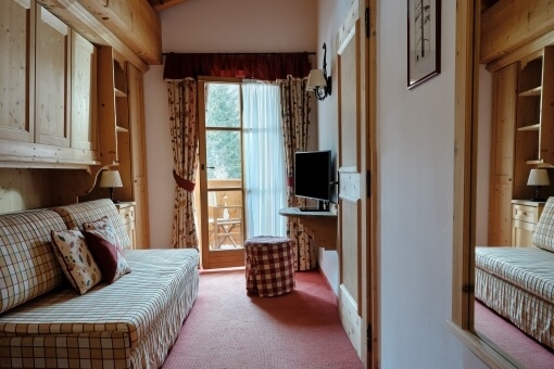 Cozy rustic room with red and white decor, checkered sofa, wooden accents, and natural light from a large window.