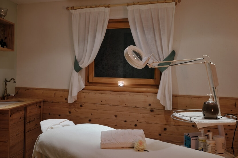 Ein sanft beleuchteter Raum mit einem Massagetisch, einer Rose, einem Tray und eleganten Dekorationen für Entspannung.