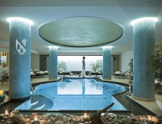 Zachwycający basen hotelowy z okrągłym basenem, kolumnami, białym dachem i naturalnymi elementami otoczenia.
