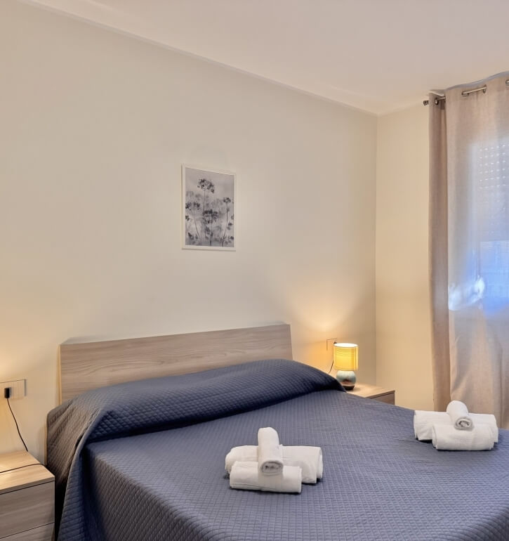 Cozy bedroom with a bed, towels, headboard, and bedside tables.