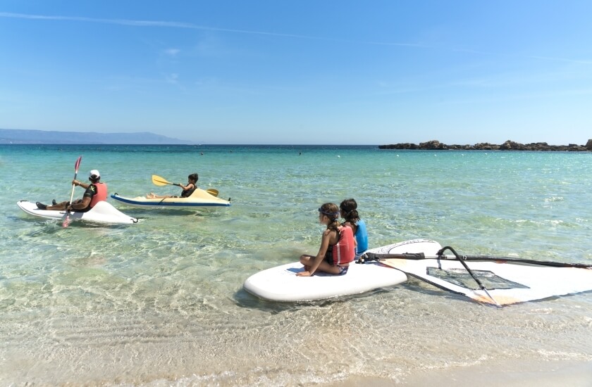 Persone in kayak e paddleboard in acque turchesi vicino a una spiaggia.
