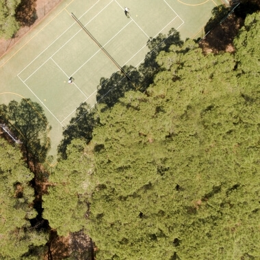Vista aerea di un campo da tennis con due giocatori in bianco.