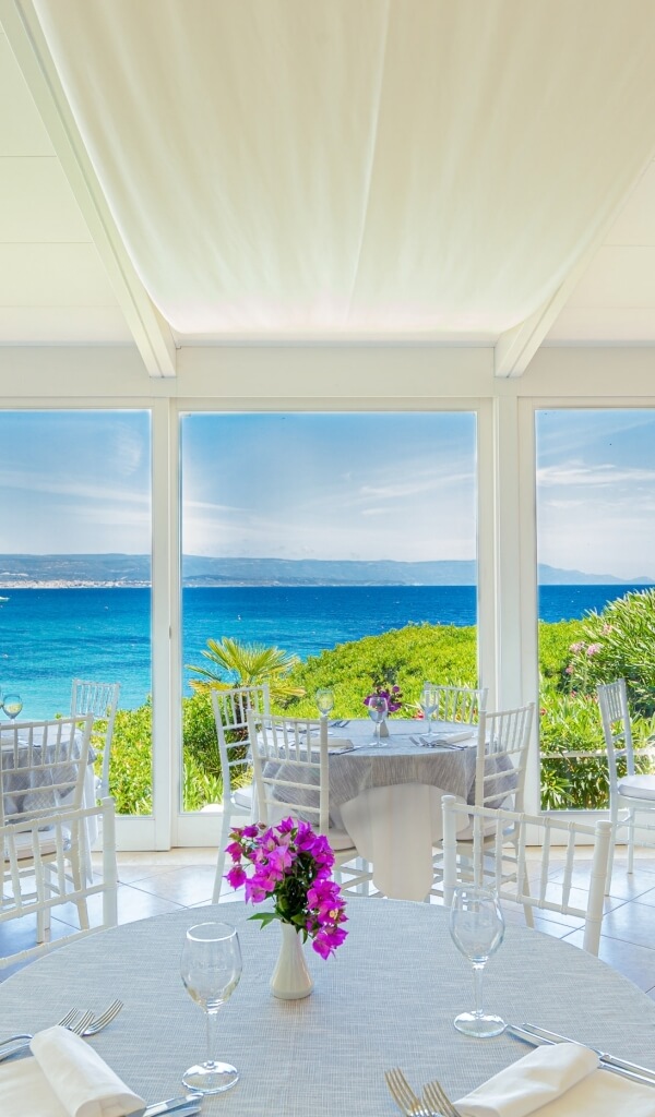 Area ristorante elegante con vista sull'oceano e tavoli decorati.