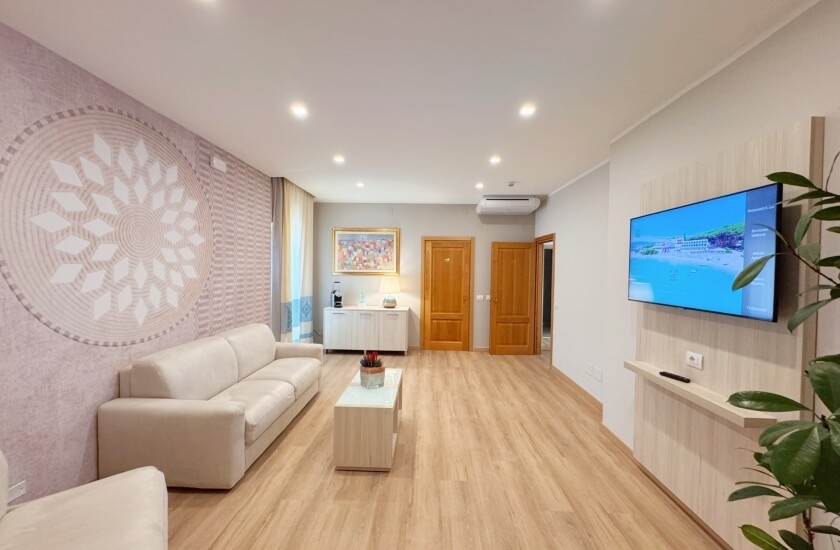Camera d'hotel con divano bianco, TV e decorazioni.