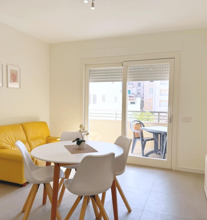 Hotel room featuring a yellow sofa, dining table, and balcony.