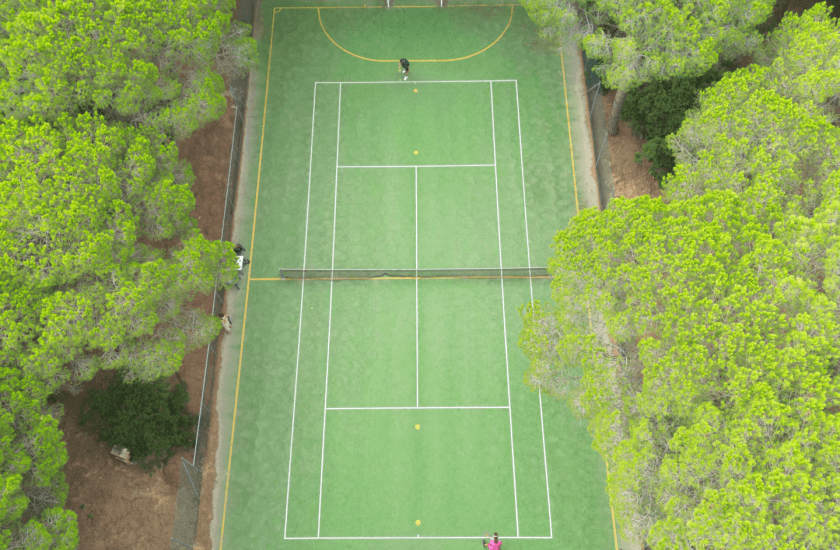 Vista aerea di un campo da tennis con tre persone e palline.