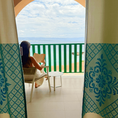 Donna con capelli lunghi legge su un balcone con vista.