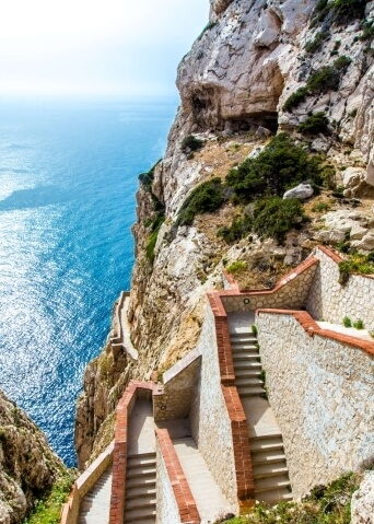 Scalinata in pietra su un cliff con vista mare blu.