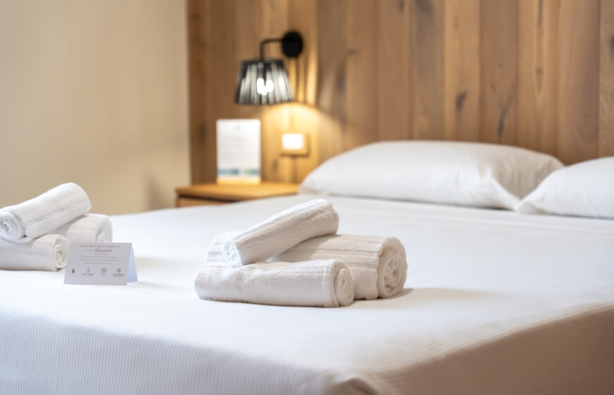 Hotel room with a white bed, wooden headboard, and bedside table.