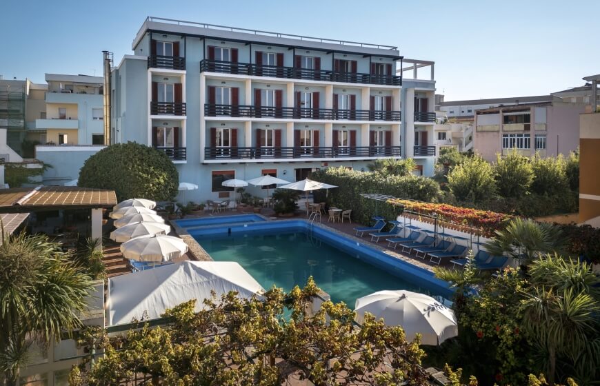 Edificio blu multi-piano con piscina all'aperto e ombrelloni.