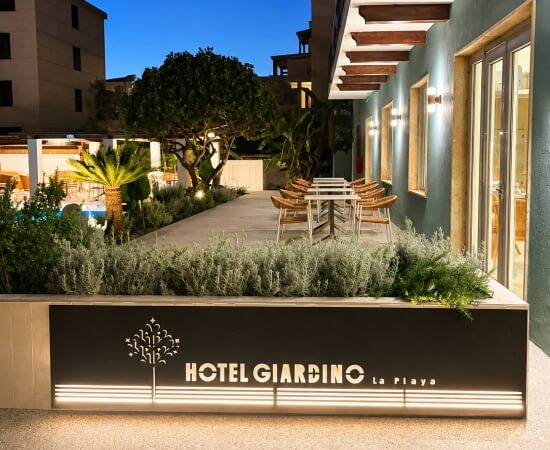 Esterno dell'hotel Giardino La Playa con piscina e tavoli all'aperto.