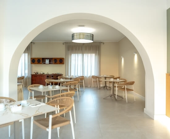 Area pranzo con tavoli, sedie, finestre e illuminazione elegante.