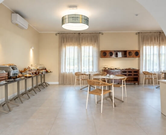 Colazione a buffet in una sala con tavoli e finestre.