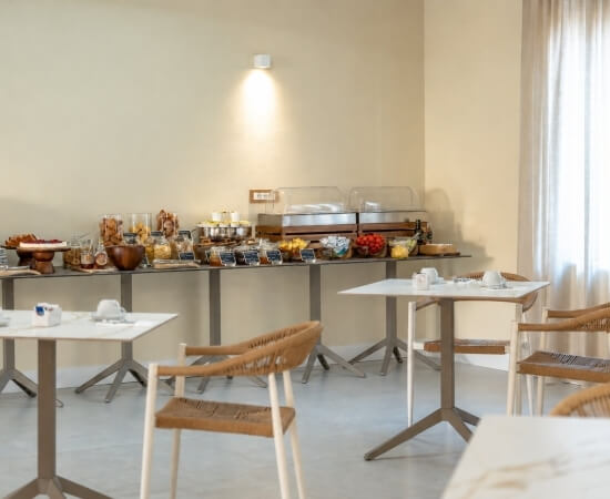 Colazione a buffet con marmellate, cereali e pasticcini su un tavolo.