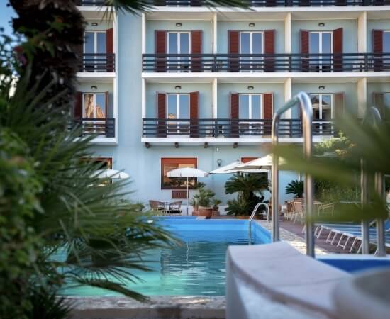 Vista di una piscina d'hotel con palme e ombrelloni.