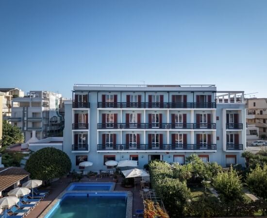 Edificio alberghiero blu con piscina, ombrelloni e lettini.