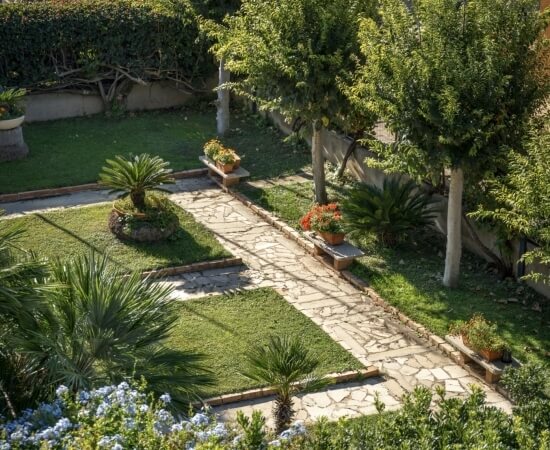 Sentiero di pietra in un giardino con piante e panchine.