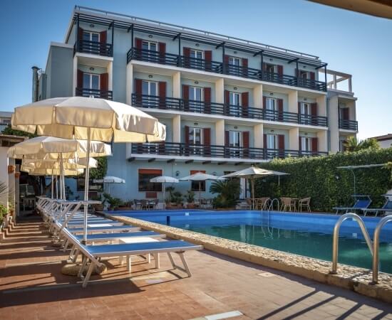 Edificio a più piani blu con piscina e lettini vuoti.