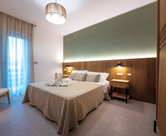 Cozy hotel room with a large bed, towel swan, and green walls.