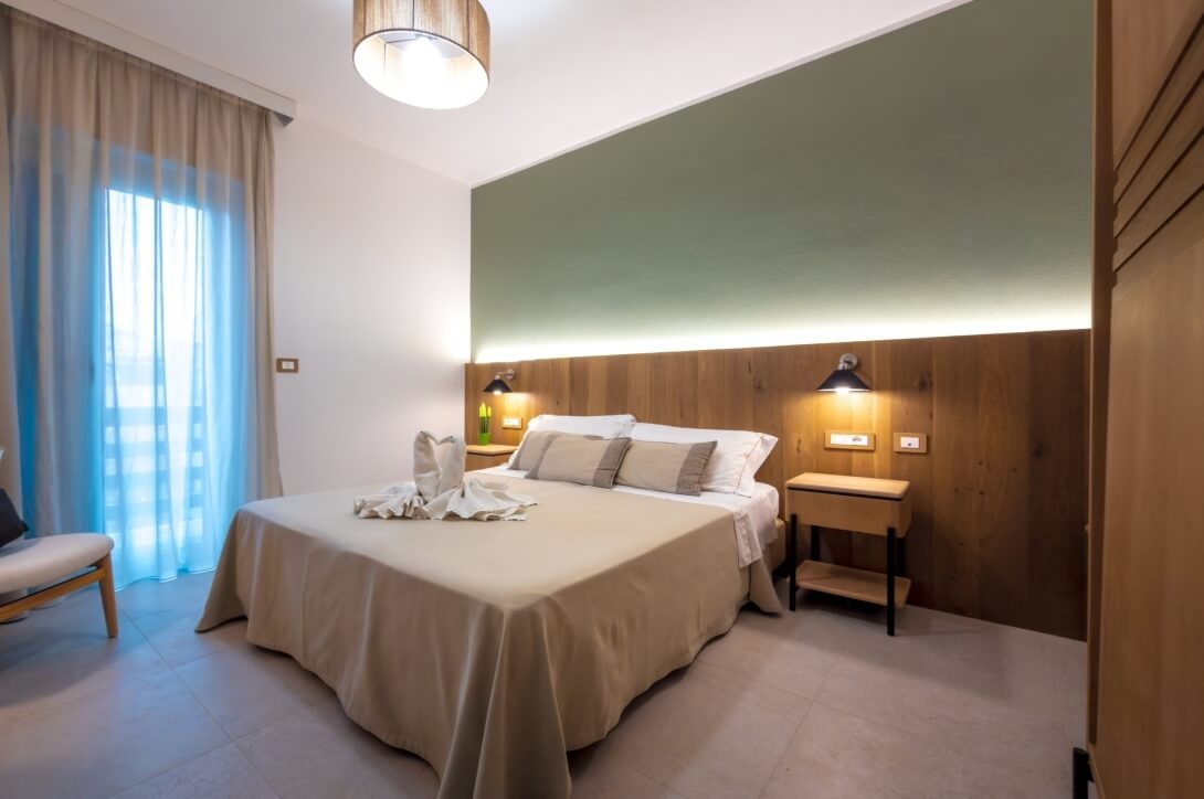 Camera d'hotel con letto, asciugamani a forma di cigno e finestre.