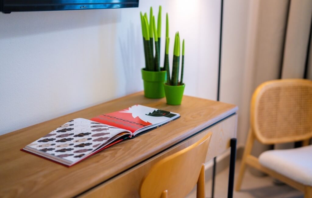 Scrivania con libro aperto, piante verdi e sedia bianca.