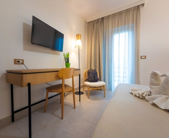 Camera d'hotel con letto, scrivania, TV e finestra.