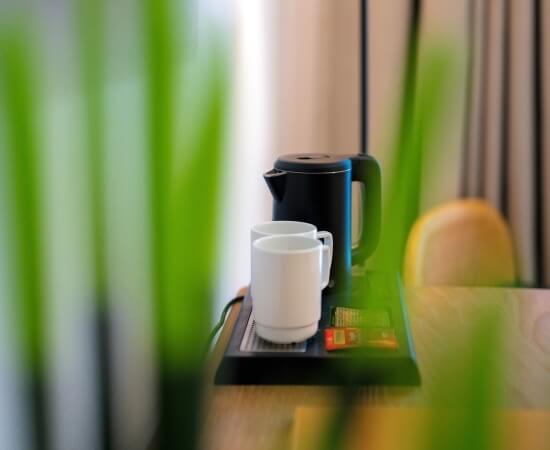 Nero bollitore elettrico con due tazze bianche su un vassoio.