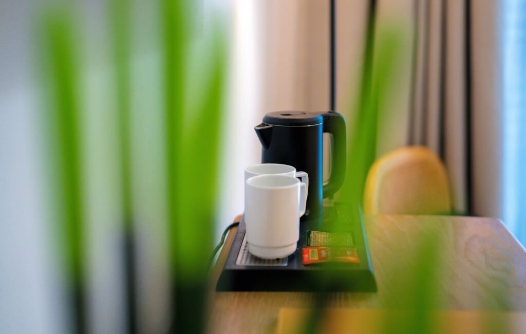 Nero bollitore elettrico con tazze bianche su un vassoio.