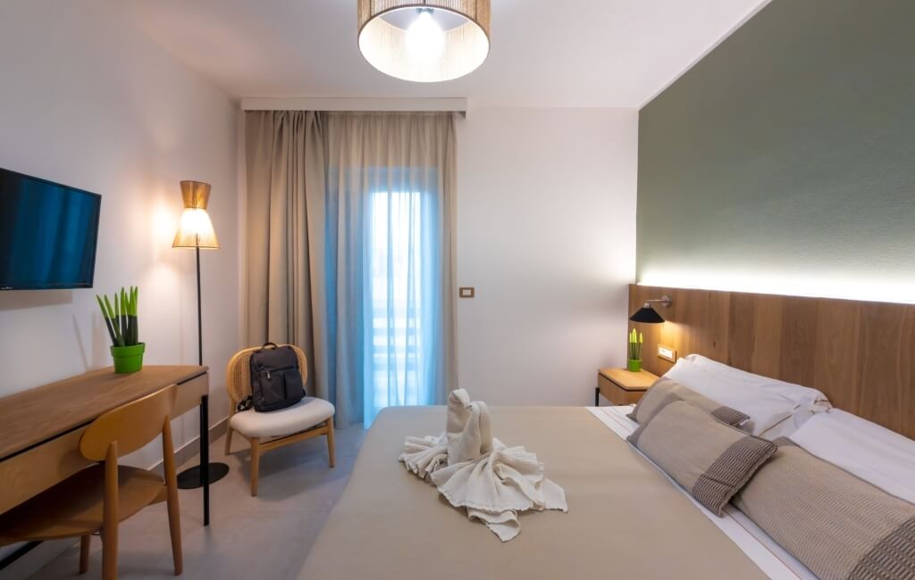 Camera d'hotel con letto, scrivania, TV e animali di asciugamano.