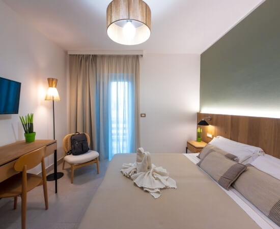 Camera d'hotel con letto, asciugamani a forma di cigni e scrivania.