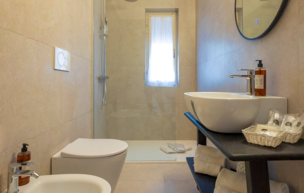 Bagno con WC, bidet, lavabo, doccia e prodotti per la cura.