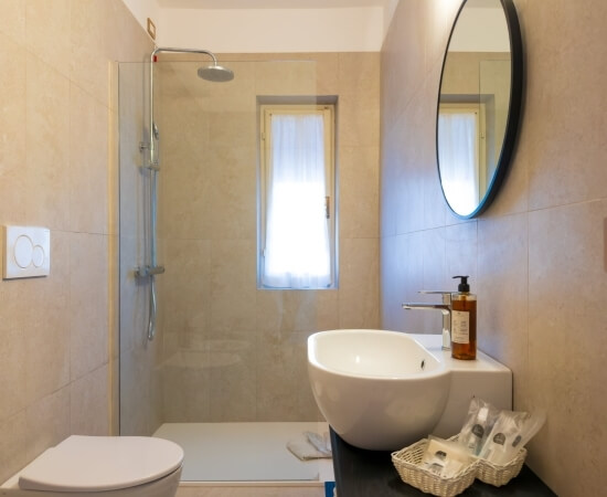 Bagno d'hotel con doccia, specchio, lavabo e finestre.