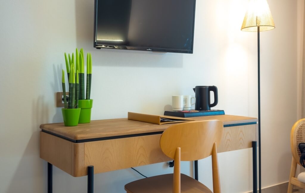 Scrivania in legno con piante, kettle, tazze e lampada.
