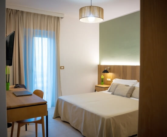 Camera d'hotel con letto, scrivania, lampade e decorazioni.