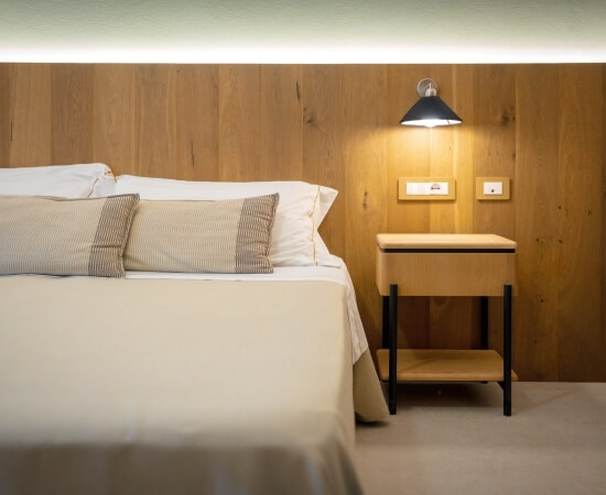 Camera d'hotel con letto, comodino e lampada a muro.