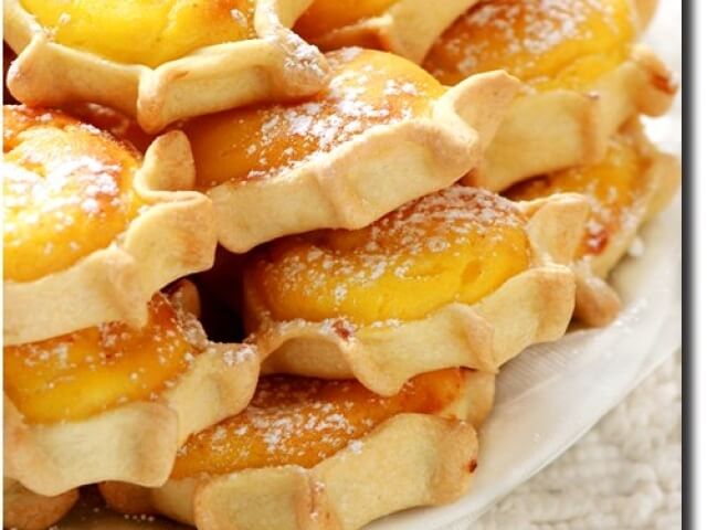 Una pila di dolci dorati con zucchero a velo su un piatto bianco, creando un'atmosfera calda e invitante.