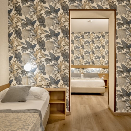 Camera da letto con carta da parati floreale, due letti, specchio e pavimento in legno chiaro, atmosfera confortevole.