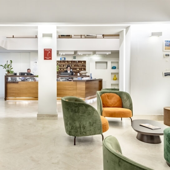 Hotel reception area with two desks, seating, and light decor.