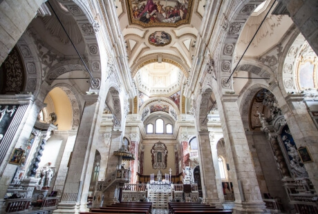 Interno di una chiesa ornata con un altare in marmo bianco, vetrate colorate e opere d'arte religiose.