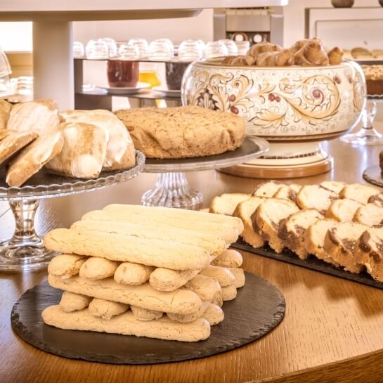 Vassoio di dolci su un tavolo di legno, con vari prodotti da forno e un'atmosfera accogliente e calda.