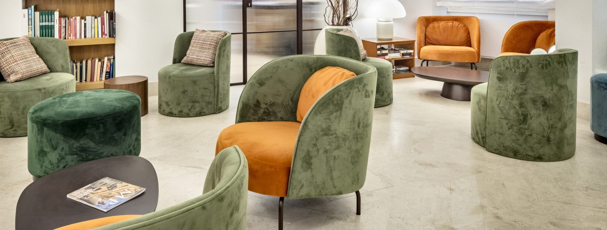 Seating area with colorful chairs, bookshelf, and coffee table.